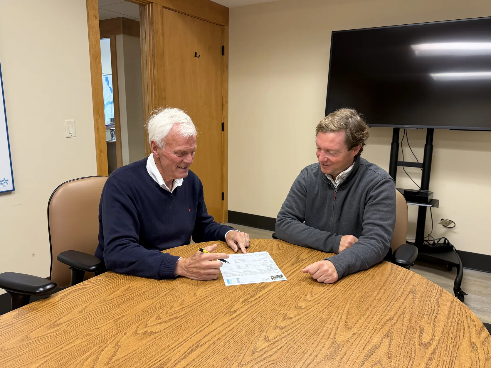 Kirk Stauss meeting with a client at a conference table in the Stauss Realty office in Okoboji, Iowa