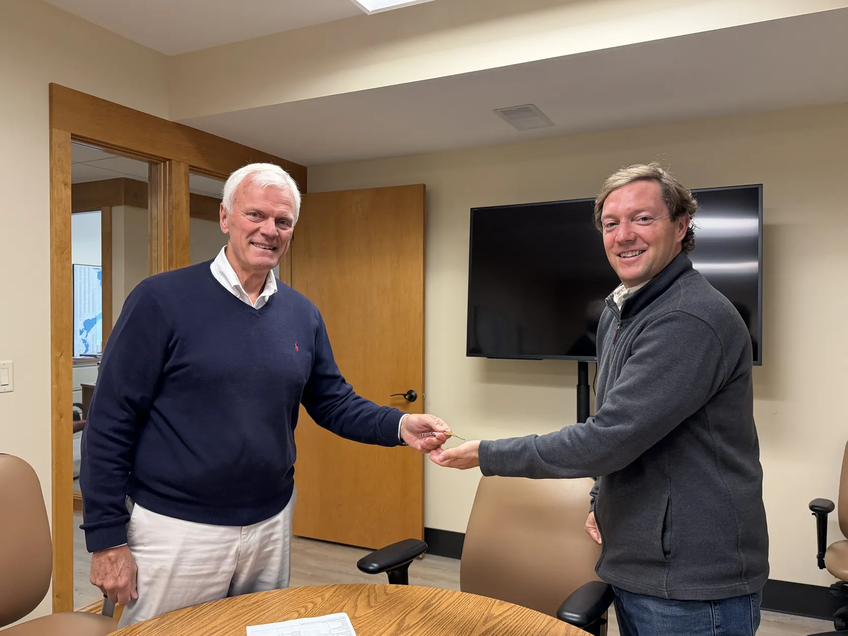 Kirk Stauss shaking hands with a client in the Stauss Realty conference room in Okoboji, Iowa