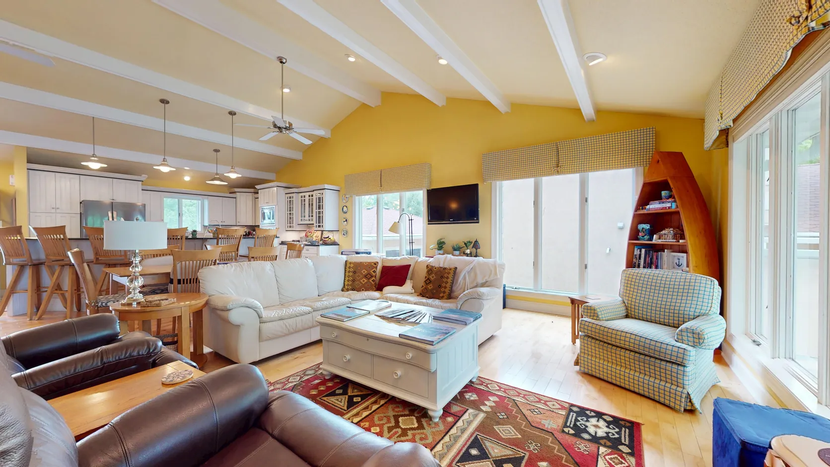 Open living room and kitchen with beamed ceiling and lake-facing windows in an Okoboji, Iowa home