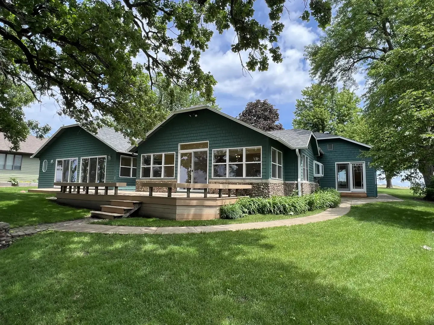 Green lakefront cottage with a wide deck and lawn facing the water in Okoboji, Iowa