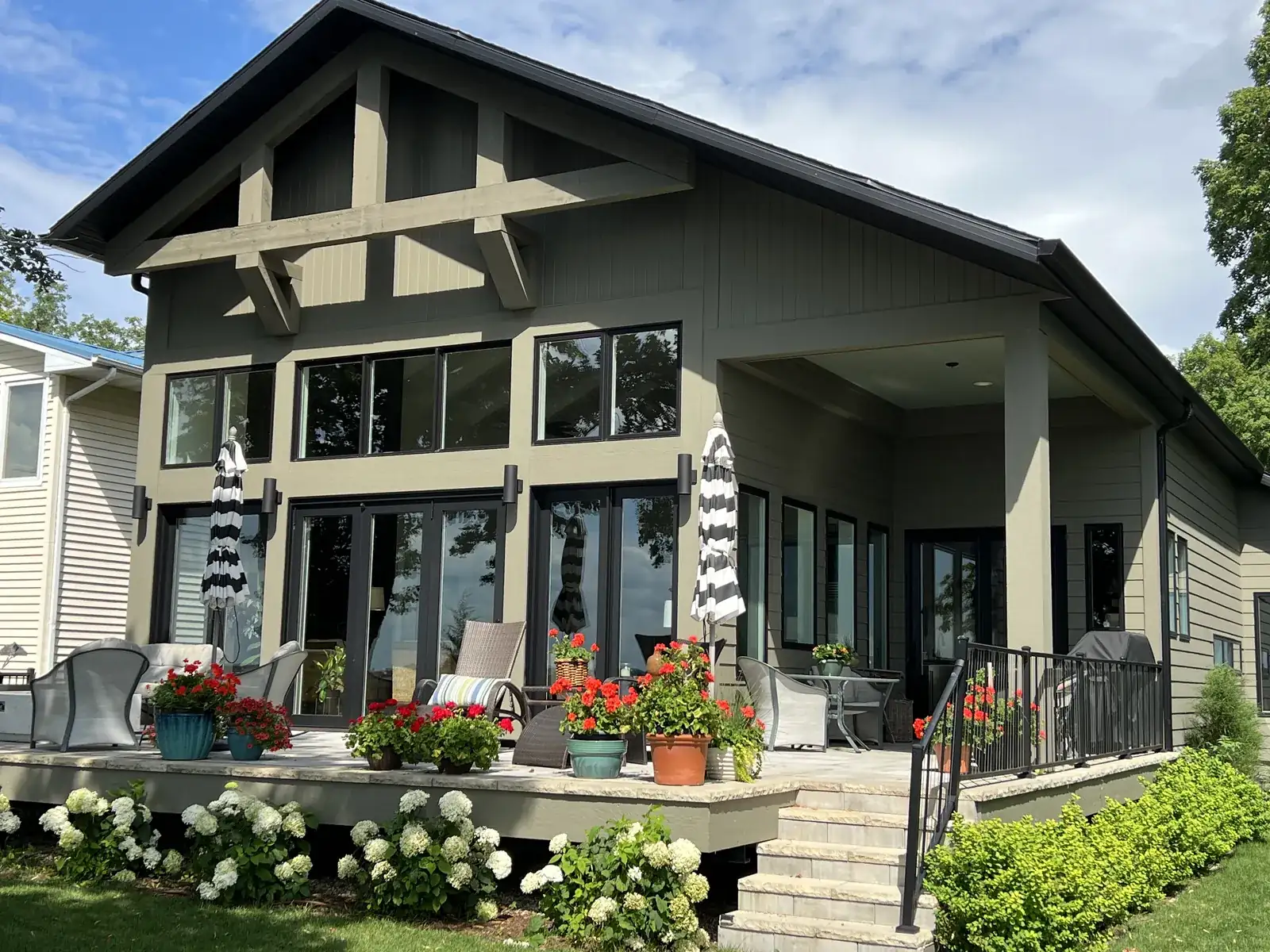 Craftsman-style lake home with tall windows and a flower-lined patio on West Lake Okoboji, Iowa